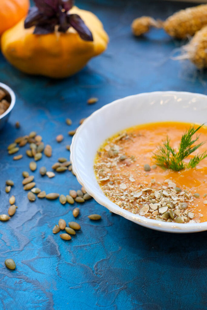 Tasty and delicious squash pumpkin soup with toasts, melted cheese, decorated with dill and pumpkin seeds in white plate against white tablecloth background. Copy space - Photo, Image