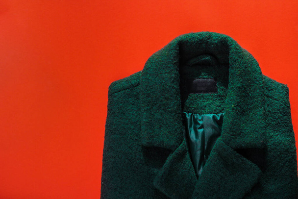 abrigo de mujer verde sobre fondo rojo. guardarropa de otoño
 - Foto, Imagen