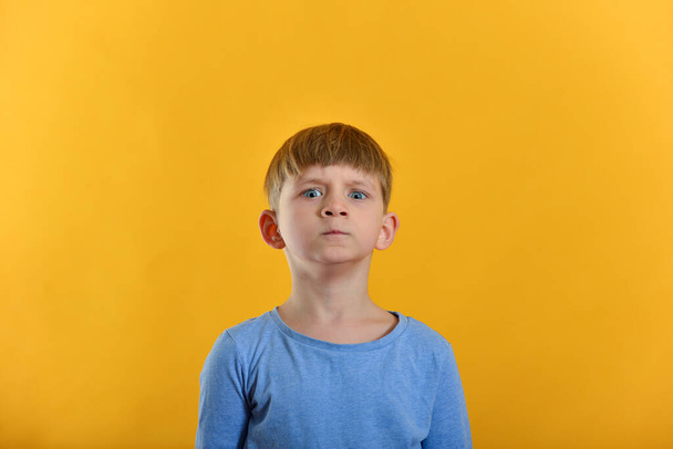 Um menino em uma camiseta azul e em um fundo laranja posando
. - Foto, Imagem