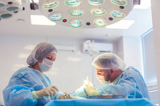 A group of surgeons works in the operating room. Two doctors perform surgery on a patient - Foto, Bild