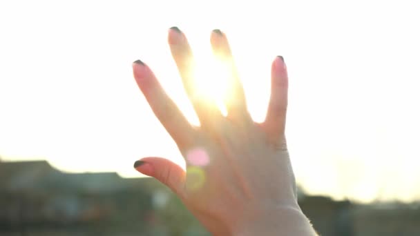 Eine Frau blickt durch ihre Hand in die strahlende Sonne. Die magischen Sonnenstrahlen scheinen durch Ihre Finger. Fantastisches helles Licht. Blitz. Eine Frau sonnt sich in der Sonne. Unachtsamkeit. Glück. Tourismus. - Filmmaterial, Video