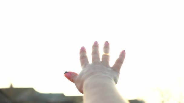 A woman looks at the bright sun through her hand. The magical rays of the sun shine through your fingers. Fantastic bright light. Flash. A woman basking in the sun. Carelessness. Happiness. Tourism. - Footage, Video