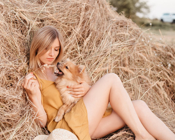 犬と一緒に干し草の玉の近くの美しい女の子。ヘイスタックを背景にした少女 - 写真・画像