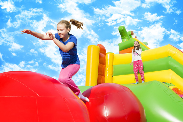 幸せな女の子はボールからボールにジャンプしながら楽しい多くを持っているインフレーション城で. - 写真・画像