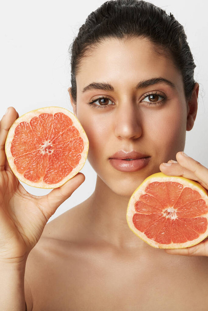 Vertical portrait of young beautiful woman with two oranges posing over white background. Healthy and clean eating.  - Foto, Bild