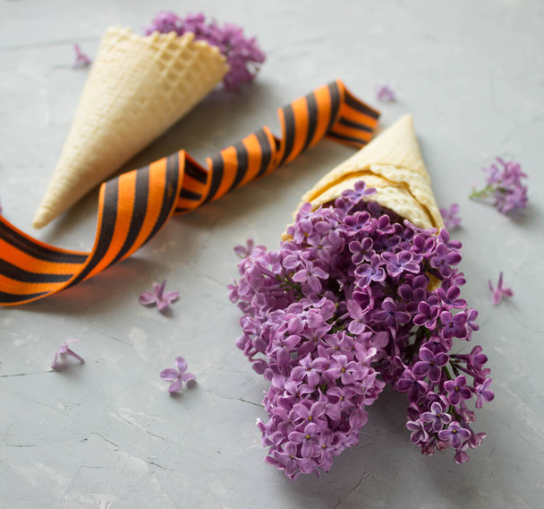 waffle ice cream cone filled with lilac flowers, concept may 9 - Φωτογραφία, εικόνα