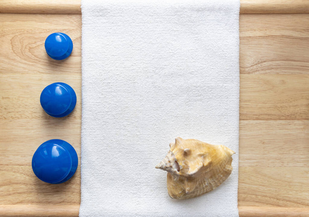 Силиконовые вакуумные банки для массажа, антицеллюлита, лица фитнеса, синий, на белом полотенце и деревянном фоне, с морской раковиной
 - Фото, изображение