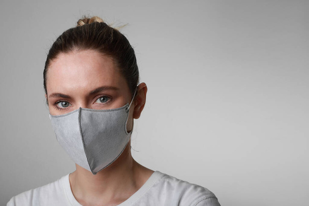 Portrait of young woman in medical face protection mask indoors on white background. Protection of the virus. - Photo, Image