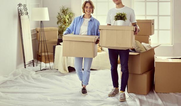 A girl and a guy holding boxes for moving the hands and looking inside box - Φωτογραφία, εικόνα