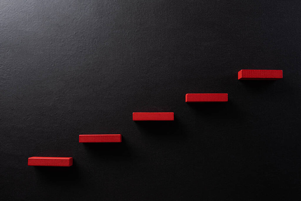 成功の基盤を構築する概念。ステップ階段としての赤い木製のブロック積層、黒の背景にビジネス成長の概念の成功. - 写真・画像