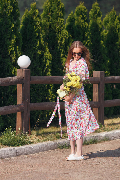 Ritratto tranquillo di una bella ragazza in piedi con un bouquet in primavera
. - Foto, immagini