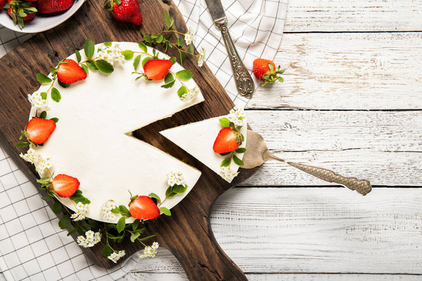 Domácí tvarohový dort zdobený jahodami na dřevěném pozadí - Fotografie, Obrázek
