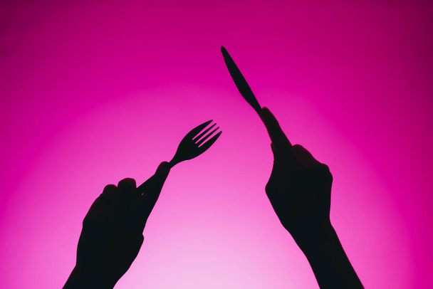 Silhouette of cutlery in hands. - Foto, afbeelding