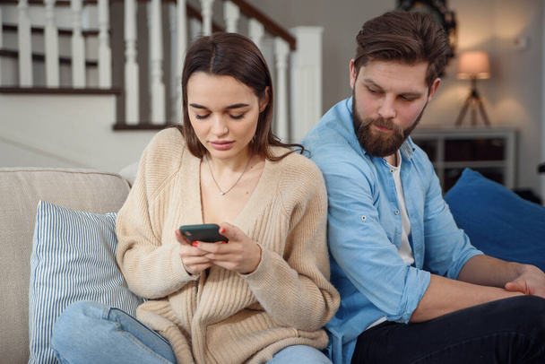 Modern couple at home. Man and woman concentrated on messaging with smartphones, ignoring each other and spending time on social media. - Photo, image