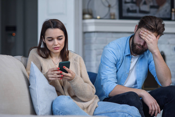 Modern couple at home. Man and woman concentrated on messaging with smartphones, ignoring each other and spending time on social media. - Foto, Bild