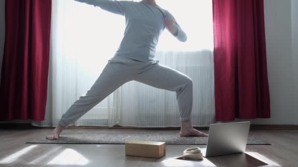 Kobieta robi trójkąt jogi poza, Trikonasana, rozciąganie ćwiczenia w domu - Materiał filmowy, wideo