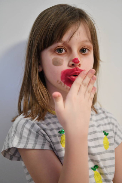 Cute little preschool girl playing with mommy's make up. Fashion experiment little child applying makeup lipstick and shadow on face, staying at home in corona virus quarantine. - Foto, Bild