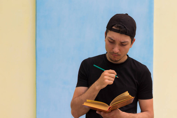 Ein Mann mit Bleistift liest sorgfältig ein Buch - Foto, Bild