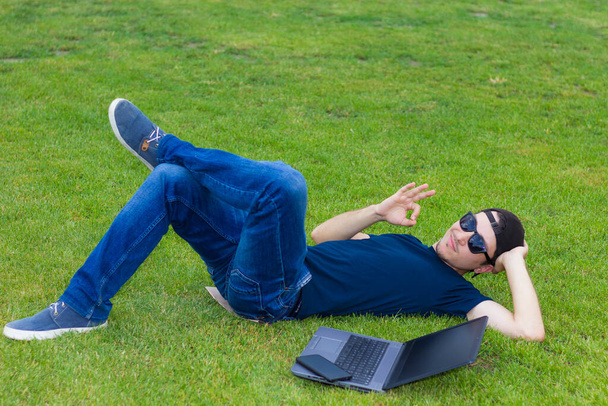 Freelancer βρίσκεται σε ένα πράσινο γκαζόν με ένα φορητό υπολογιστή - Φωτογραφία, εικόνα