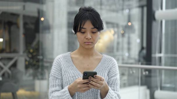 Handheld portrait shot of asian female scrolling phone - Foto, Bild