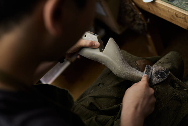 Bir ayakkabıcı atölyesinde bir ayakkabı kalıbını tıraş eder. - Fotoğraf, Görsel