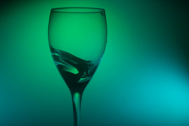 Water splash in glass on glowing background. splashing water in wine glass. transparent cocktail - Foto, Imagen