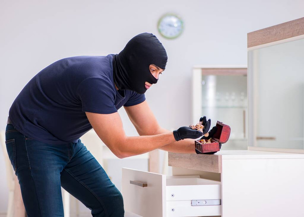Ladrão usando balaclava roubando coisas valiosas - Foto, Imagem