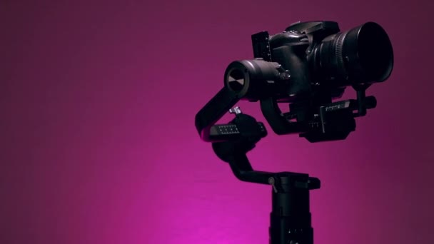 Σταθεροποιητής ή Gimbal με συναρμολογημένη κάμερα, κάνοντας κινήσεις εγγραφής με έγχρωμο φόντο - Πλάνα, βίντεο