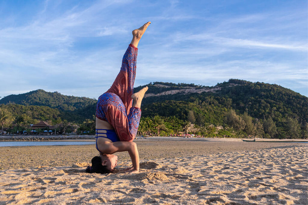 Asiatische Thailänderin praktiziert abends Yoga am Strand von Mae Haad auf der Insel Koh Phangan, Thailand. Kopfstand-Stativstellung - Foto, Bild