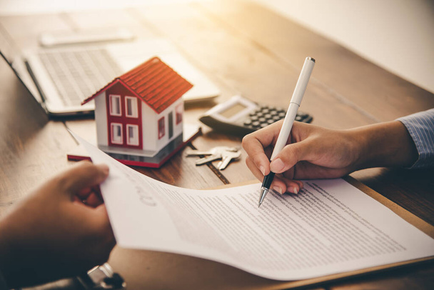 Подписавшие договор подписывают кредитный документ на право собственности на дом с агентами по недвижимости. Ипотека и инвестиции в недвижимость, страхование жилья - Фото, изображение