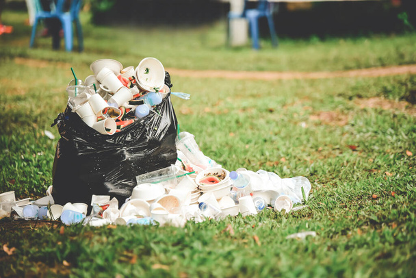 Schaumstoffboxen, Essensreste und Plastikflaschen, die vor dem schwarzen Müllsack überquellen, verschmutzen die Gegend. Das Konzept sauber halten - Foto, Bild