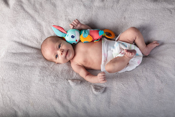 muito sorrindo bebê menina e brinquedo coelho deitado no fundo de luz
 - Foto, Imagem