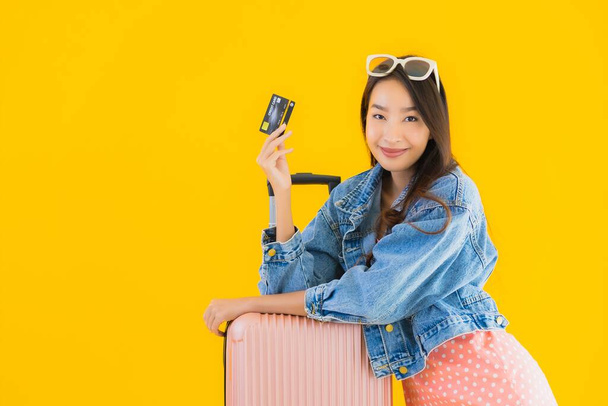 Retrato bela jovem mulher asiática com bagagem saco de viagem com passaporte e bilhete de embarque no fundo isolado amarelo
 - Foto, Imagem