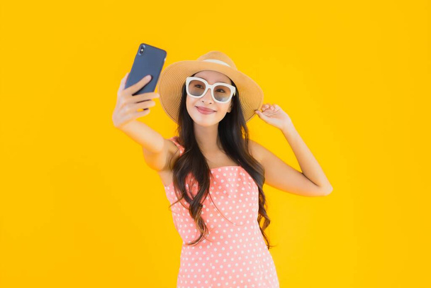 Porträt schöne junge asiatische Frau verwenden Smartphone auf gelbem isolierten Hintergrund - Foto, Bild