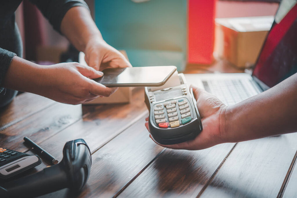 Rachunek płacony przez klienta za pomocą smartfona przy użyciu technologii NFC. Zbliżenie płatności za pomocą maszyny bezdotykowej. - Zdjęcie, obraz