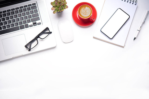 Vista superior com mesa de trabalho com laptop, celular, lápis de notebook xícara de café e óculos no escritório
.  - Foto, Imagem