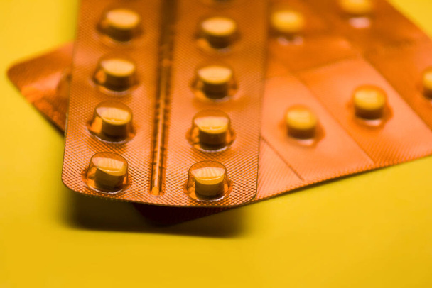 dos paquetes de pastillas de color naranja visto de cerca y un fondo de color amarillo
 - Foto, Imagen