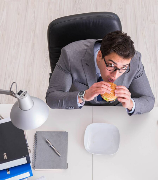 Hungry funny businessman eating junk food sandwich - Фото, зображення