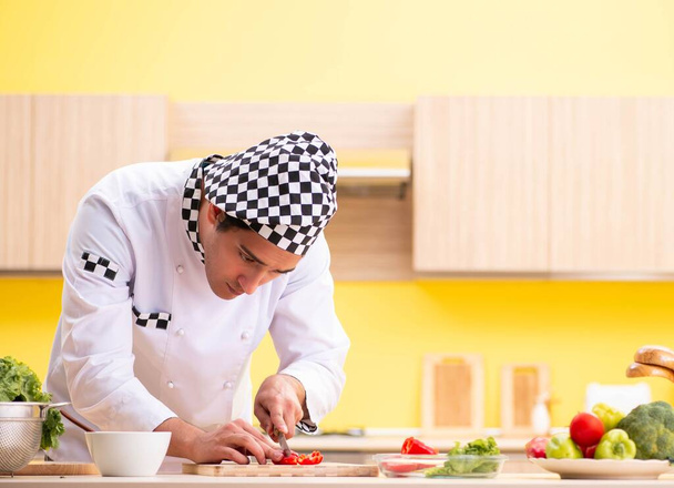 Joven cocinero profesional preparando ensalada en casa - Foto, imagen