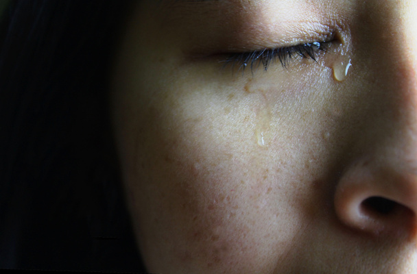 Zbliżenie pół twarzy Azjatki płaczącej ze łzami, odizolowanej na ciemnym tle. Pojęcia emocji i ekspresji człowieka. - Zdjęcie, obraz