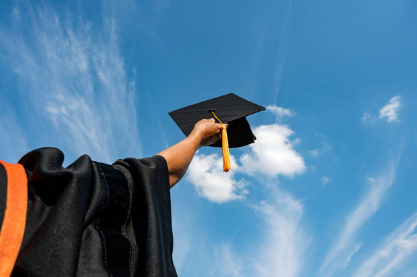 Mezuniyet şapkasını ellerinde tutan öğrenciler tören sırasında parlak bir gökyüzünde üniversiteden mezun oldular, Yüksekokulda Başarılı Eğitim Konsepti,  - Fotoğraf, Görsel