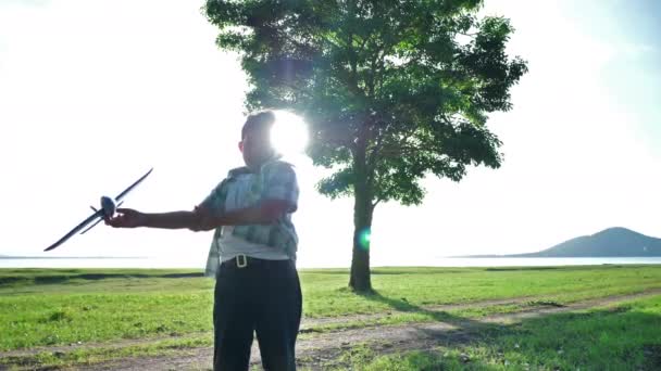 Menino asiático feliz está jogando jogando jogar avião simular na natureza, árvores e pradarias ao ar livre que tem luz solar à noite. Férias de felicidade Movimento lento
 - Filmagem, Vídeo