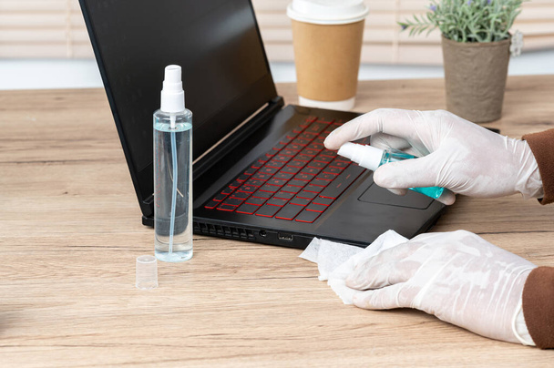 Männer tragen weiße Handschuhe, benutzen Alkohol und Spachteltuch, um ihre Laptops zu reinigen, um Viren zu verhindern. - Foto, Bild