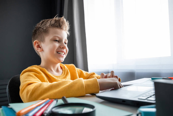 Distance learning, a boy learns math while looking at a laptop beech during an online lesson. The concept of online education, home education, technology, quarantine, self-isolation - Φωτογραφία, εικόνα