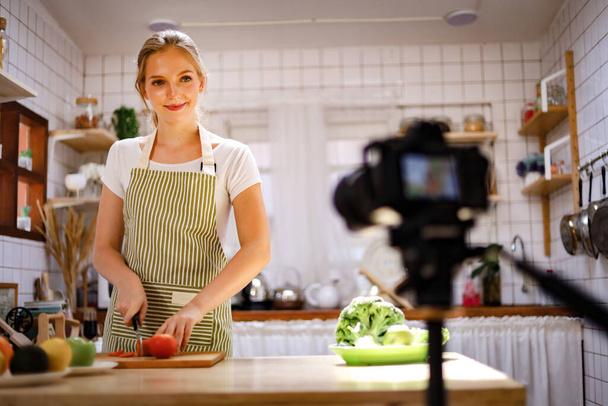 美しい若い女の子vloggerは家から働くための台所で調理を住んでいます。COVID-19 - 写真・画像