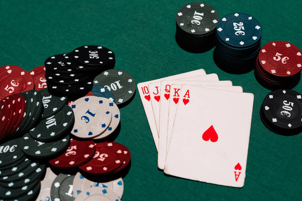 winning a game of poker at the casino. Royal flush and a Bank of chips on the background of the green table - Photo, image