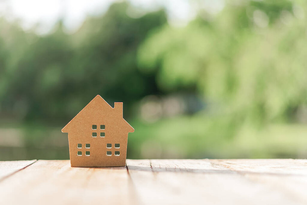 Small home model on wooden table with nature green bokeh abstract background. Family life and business real estate concept. Vintage tone filter effect color style. - 写真・画像