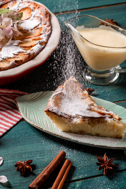 Apfelkuchen mit Zimt auf dem Tisch, ein Stück Apfelkuchen mit Kondensmilch auf einem weißen Teller. Scheibe leckerer frisch gebackener rustikaler Apfelkuchen. - Foto, Bild