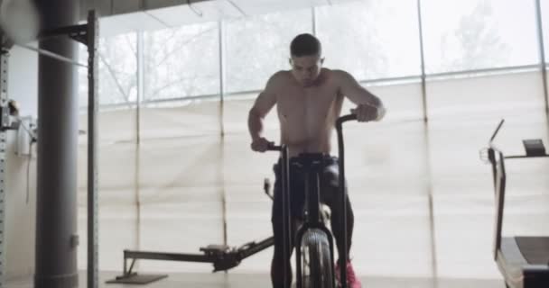 Entrenamiento con bicicleta cardio intensa, ejercicio en gimnasio cerrado. Hombres haciendo ejercicio cardiovascular difícil con airbike
 - Imágenes, Vídeo