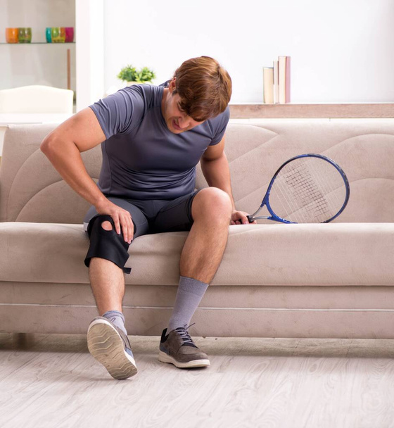 Injured man recovering at home from sports injury - Fotoğraf, Görsel